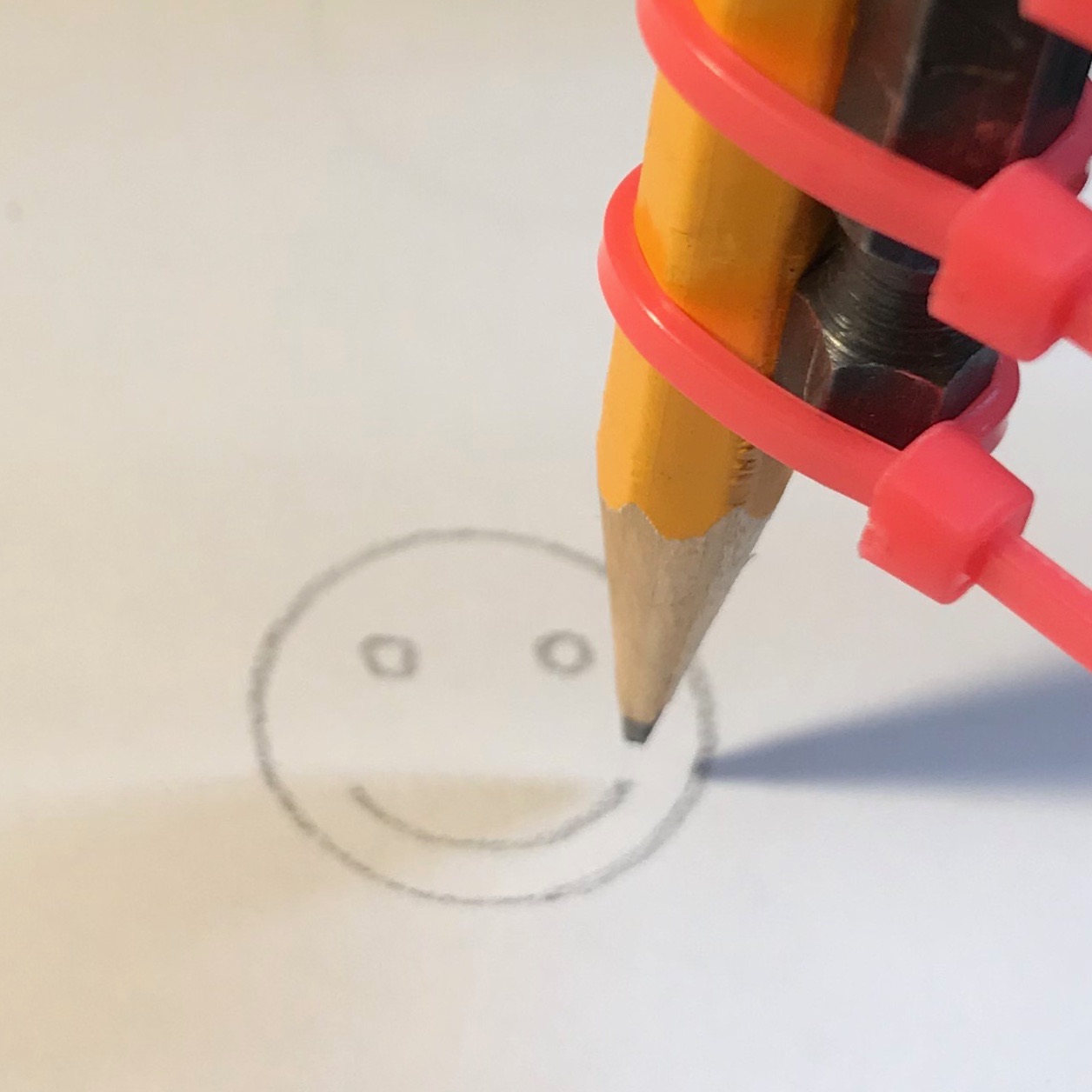 Picture of a CNC machine drawing a smiley face with a pencil